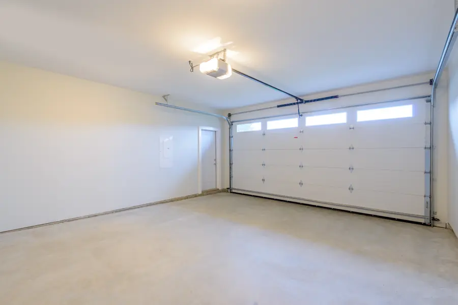 A garage interior lit by a ceiling light, with a door opener overhead