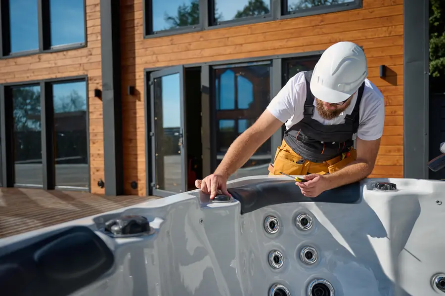 A technician in a hard hat working at an outdoor hot tub