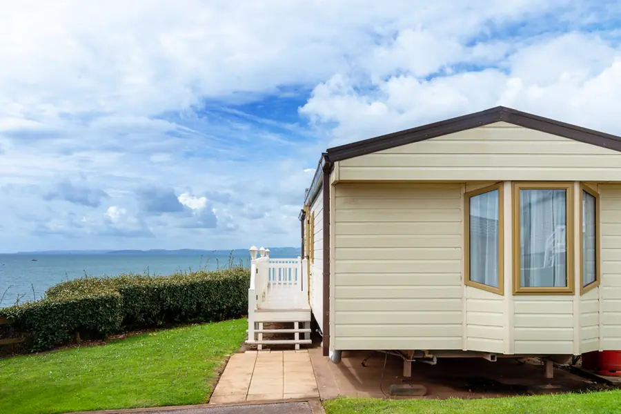A mobile home on a grassed lot overlooking the water